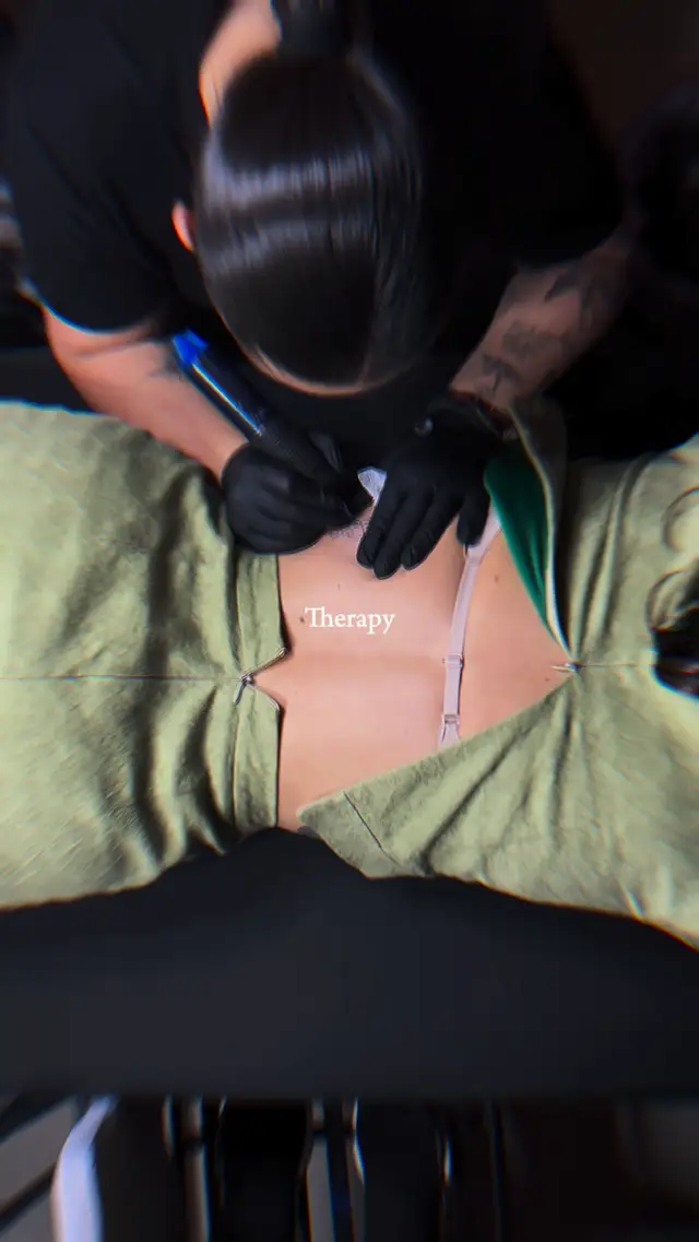 Plano cenital de Alba tatuando una palabra en cursiva fina en la espalda de una clienta